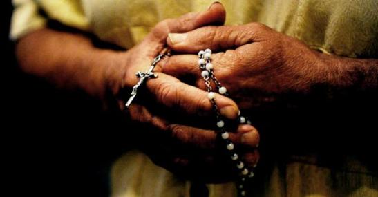 hombre-sostiene-rosario-manos-rezando-entre-dedos