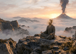 Person sitting cross-legged meditating on a rocky mountain peak during sunrise