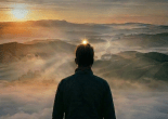 Silhouette of a person on a hill with glowing heart-shaped light on chest and sunrise background